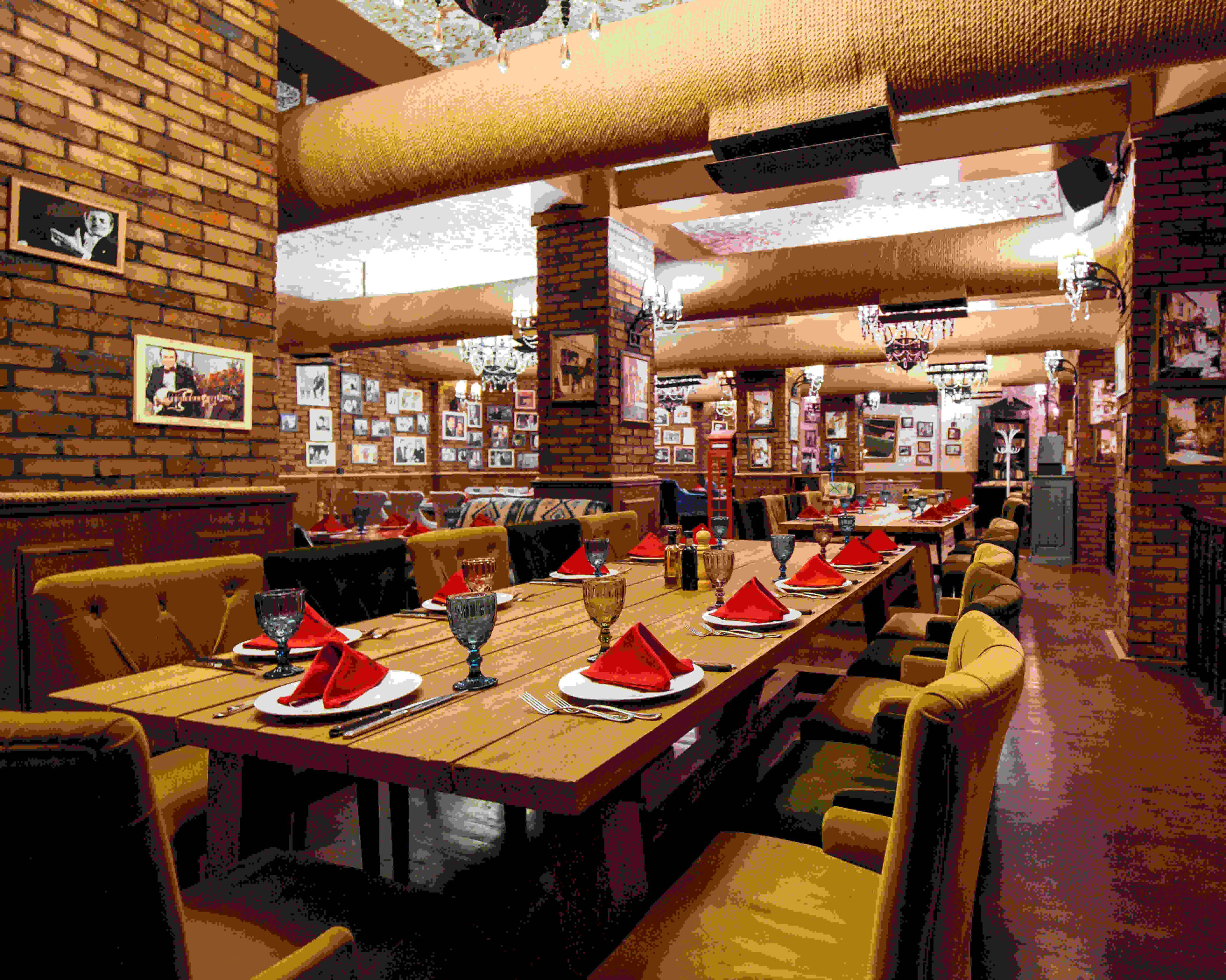 a restaurant hall with red brick walls wooden tables and pipes in the ceiling